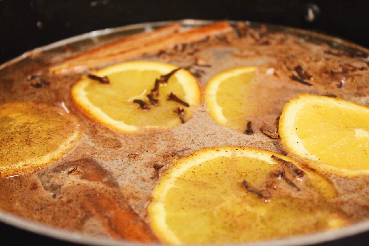 Apple cider simmering with cloves and oranges.