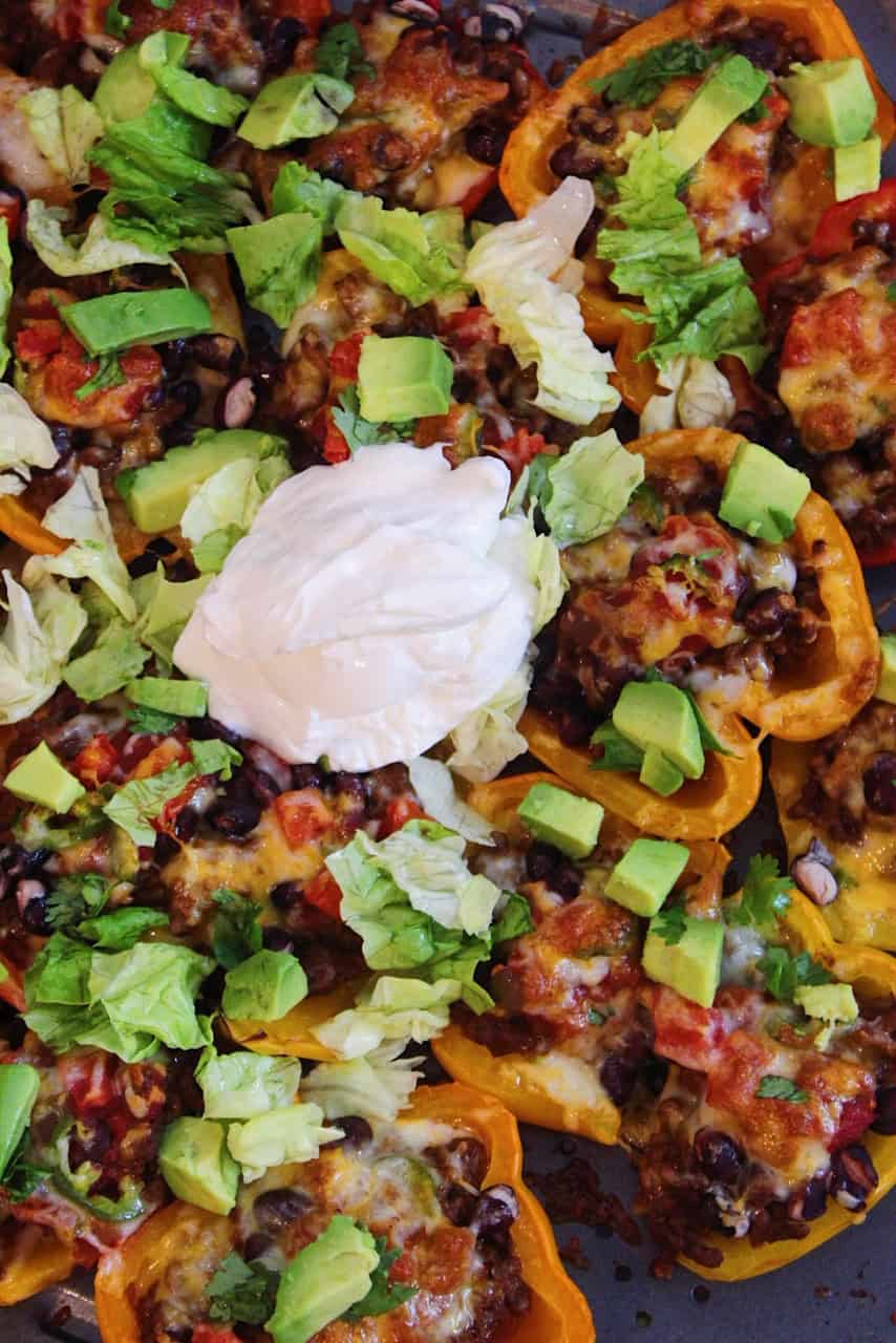 Close up image of roasted bell pepper nachos topped with avocado and sour cream.