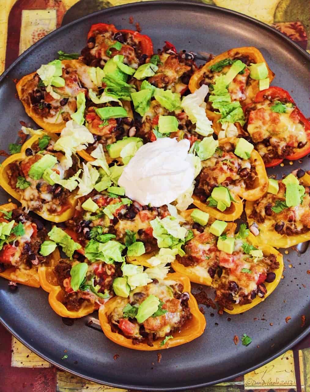 Overhead image of bell pepper "nachos" topped with meat, cheese, sour cream, avocado, and more.