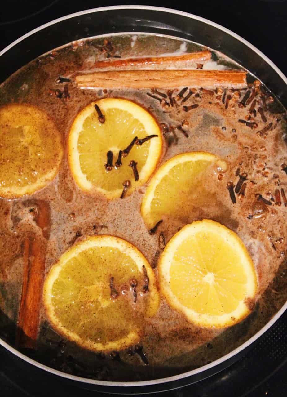 Simmering apple cider with oranges and cinnamon sticks.