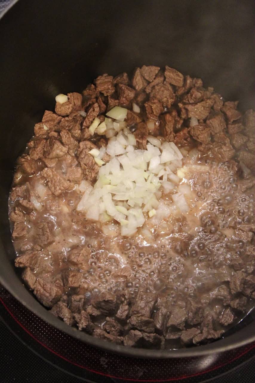 Browning stew meat with onions and garlic in a large pot.