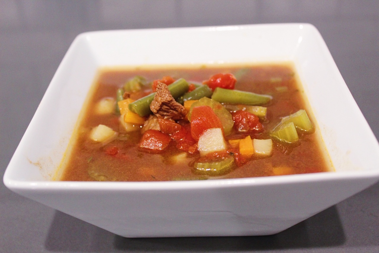 Old Fashioned Vegetable Beef Soup in a white bowl on a grey countertop.