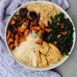 Fall harvest bowls containing rice, roasted vegetables, kale, and cheese in a white bowl.