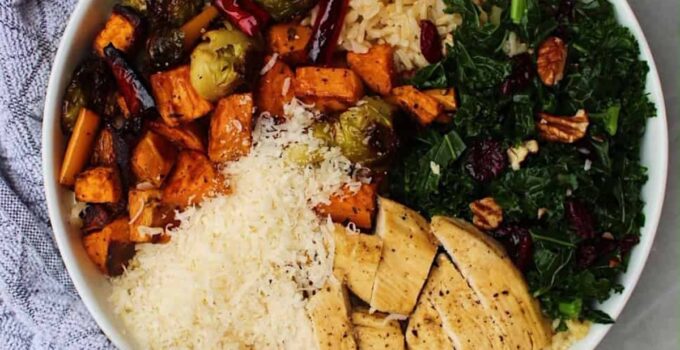 Fall harvest bowls containing rice, roasted vegetables, kale, and cheese in a white bowl.