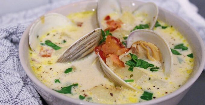 Close up picture of homemade New England Clam Chowder topped with fresh clams, bacon, and parsley.