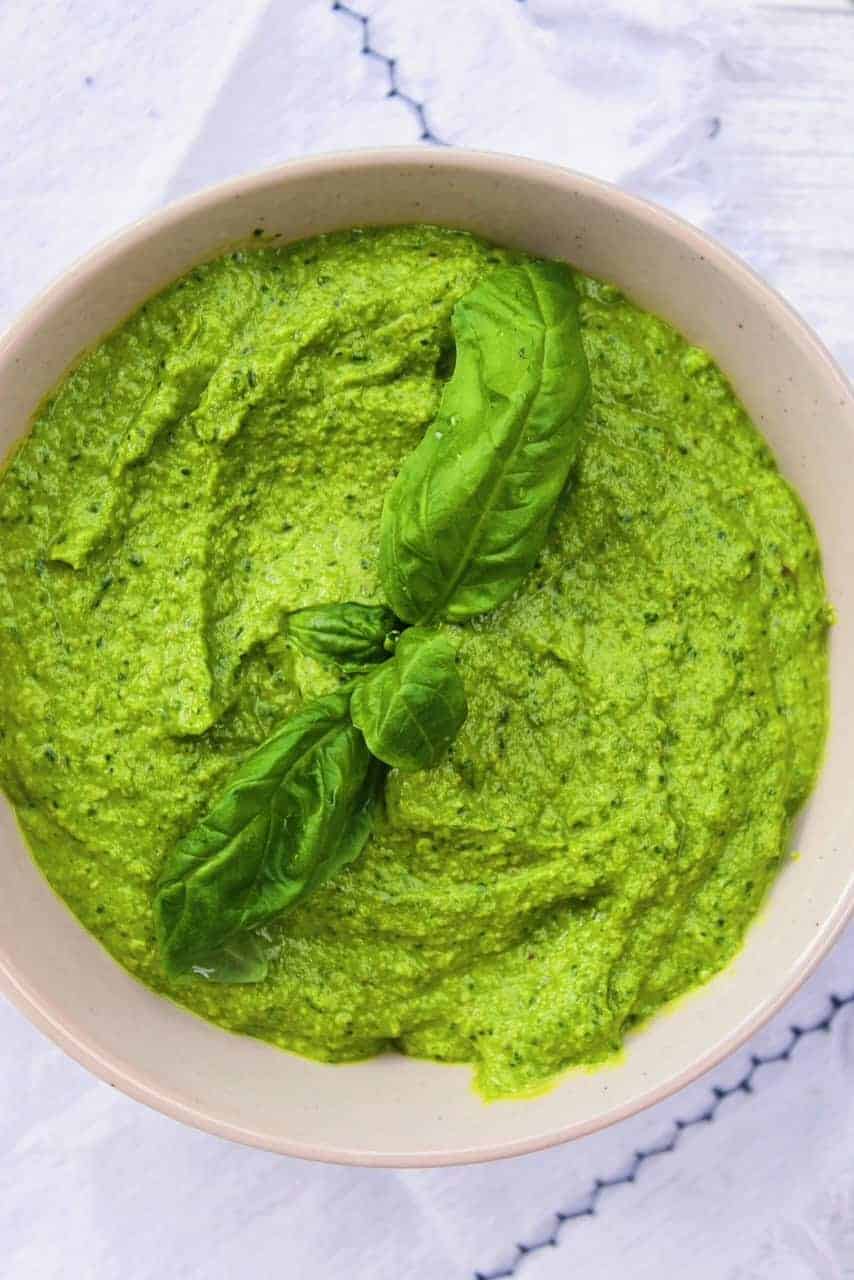 Close up of pesto topped with basil leaves.