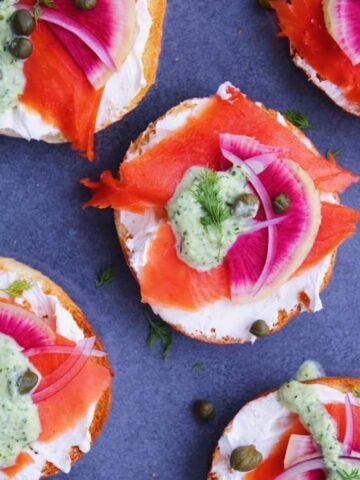 Bagels with lox and toppings on a grey plate.