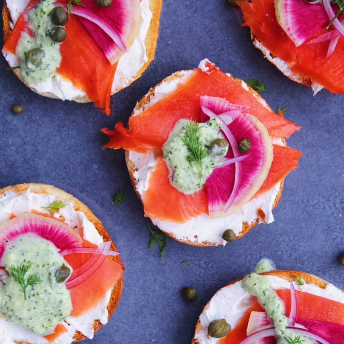 Bagels with lox and toppings on a grey plate.