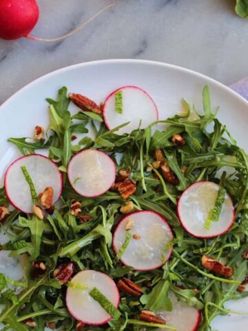 Radish salad with honey mustard vinaigrette on a white plate.