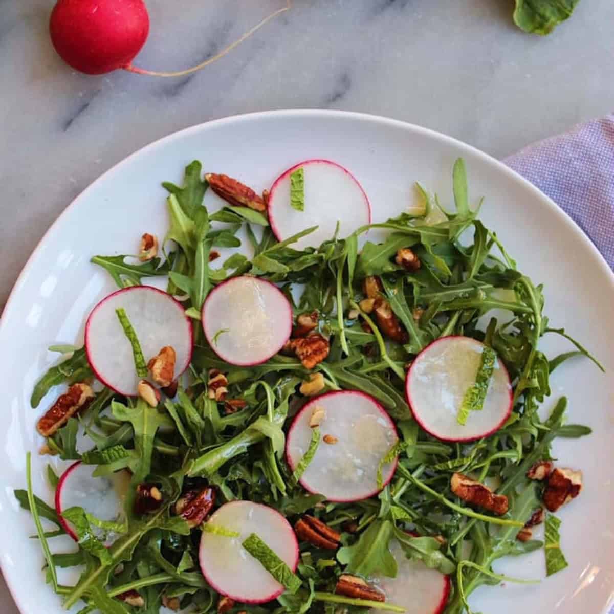 Radish salad with honey mustard vinaigrette on a white plate.