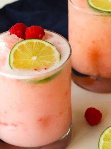 Raspberry coconut margaritas garnished with lime and raspberries.