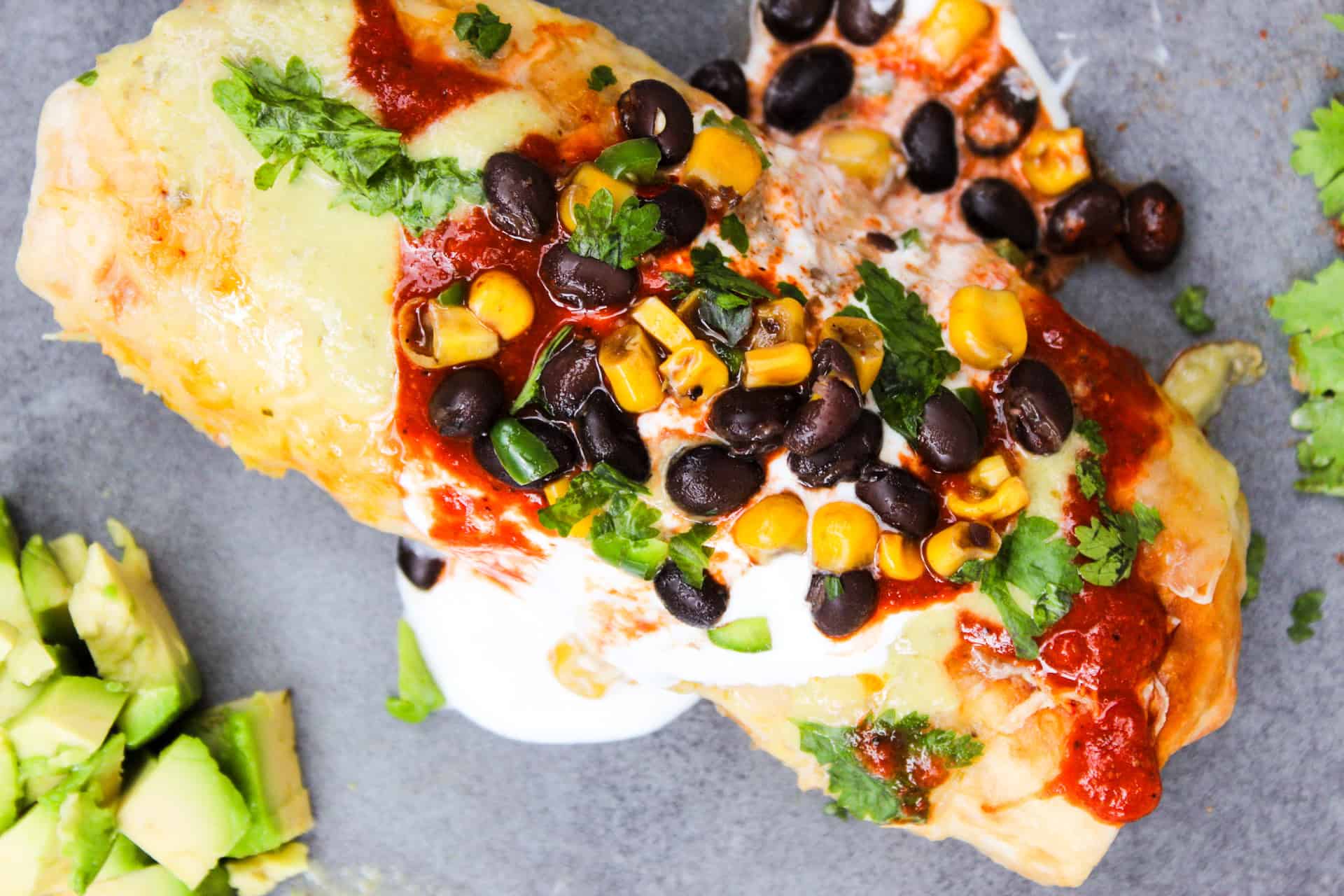 Chimichanga served with black beans, corn, sour cream, and hot sauce.