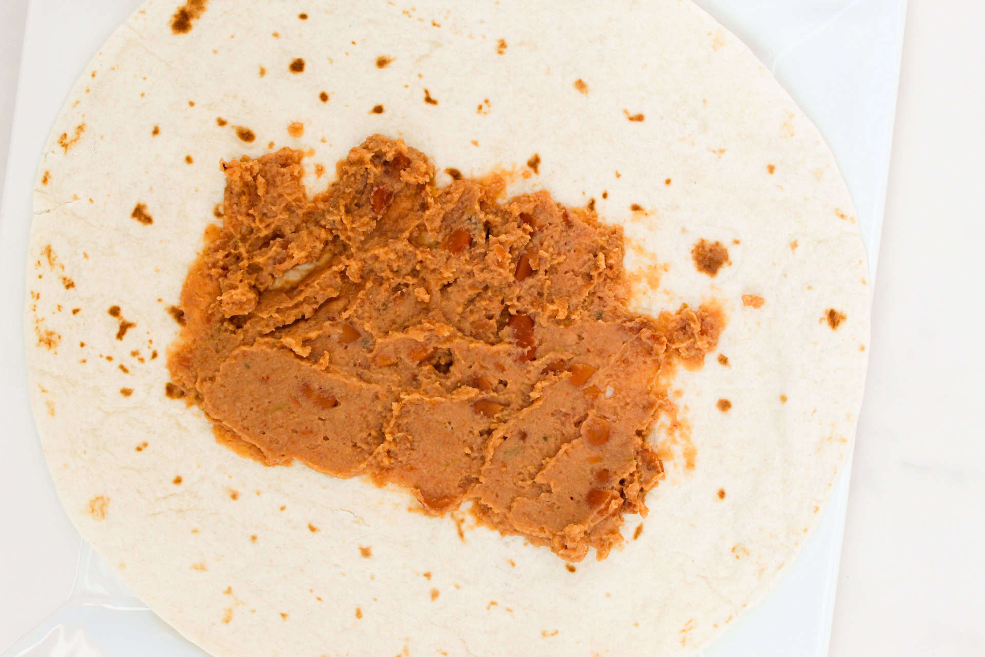 Refried beans on a flour tortilla.