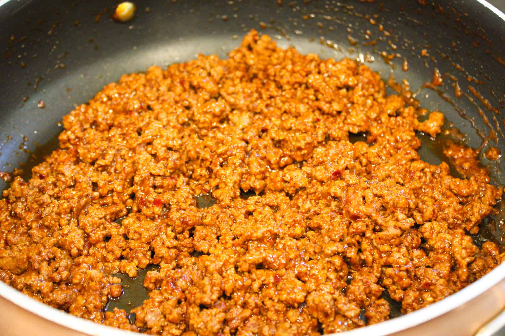 Ground beef cooking in a large skillet.