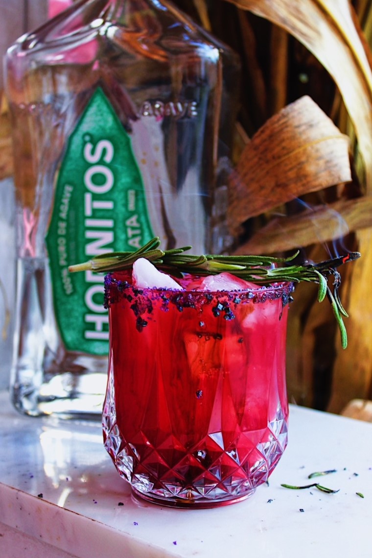 Bright red-purple Halloween Margarita in a rocks glass with sugar and rosemary garnish.