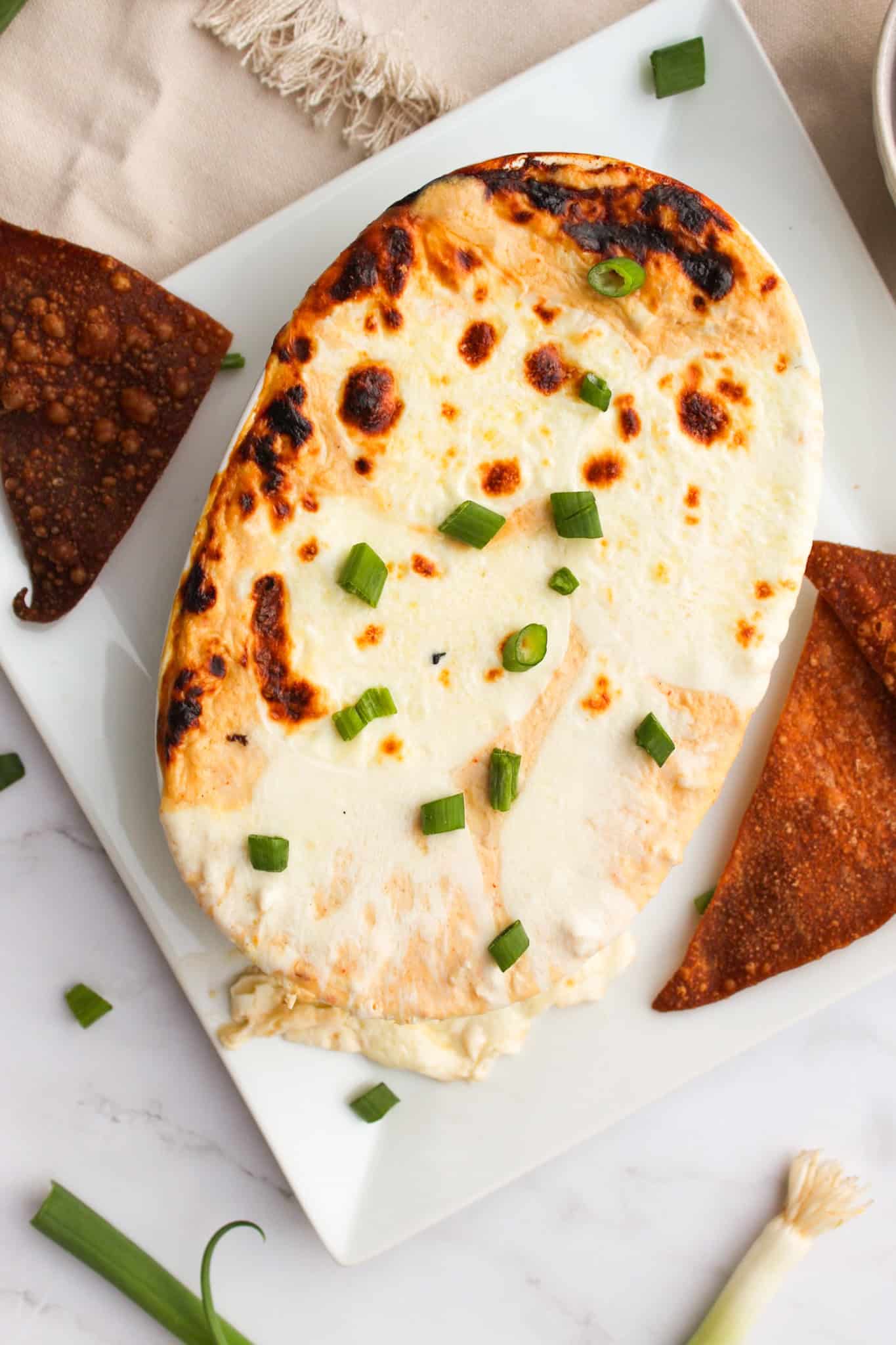 Crab Rangoon Dip topped with green onion and served with chips.